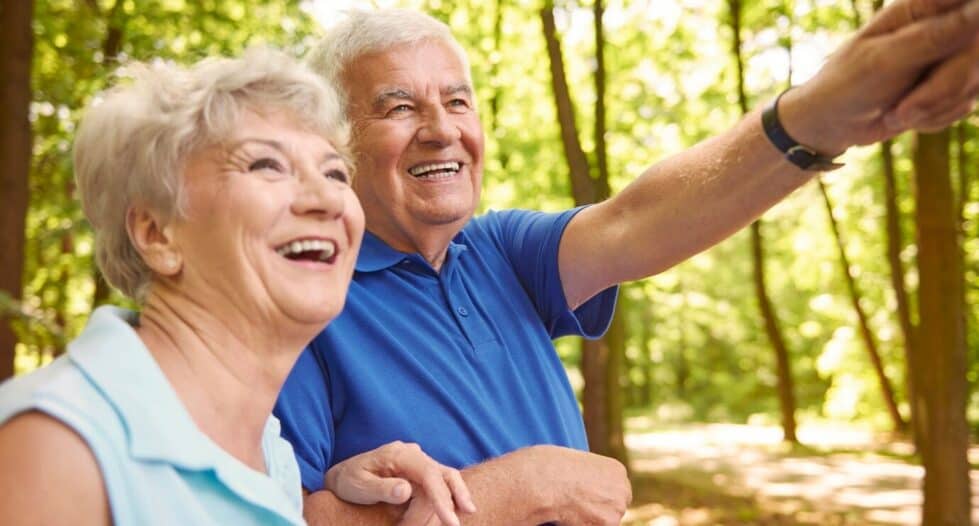 couple de seniors heureux dans les bois qui regardent au loin