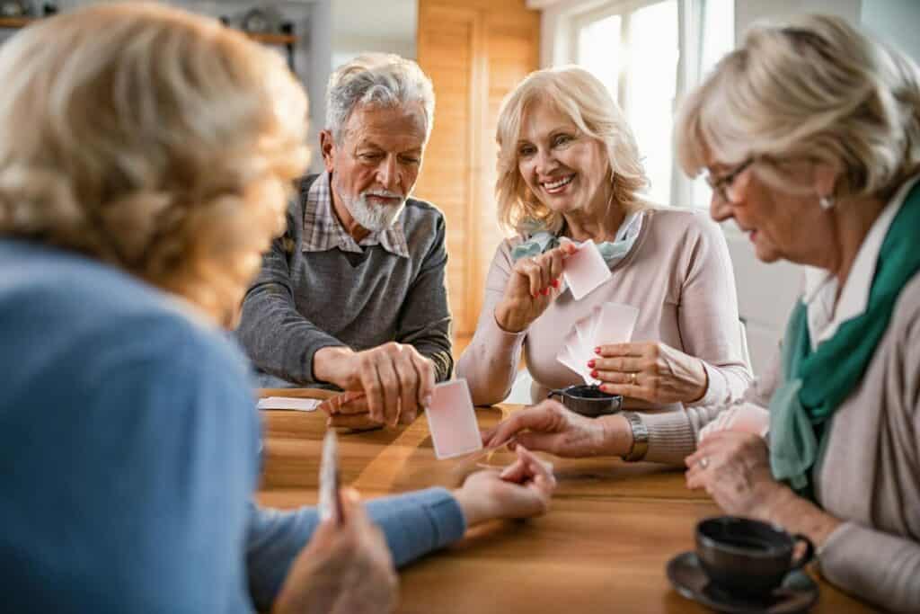 groupe de quatre séniors jouant aux cartes à l'intérieur d'une maison