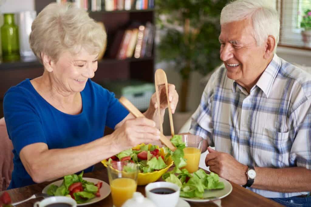 couple de seniors heureux à table en train de se servir à manger